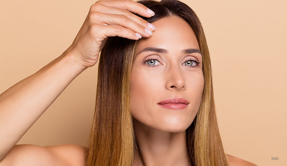 Female touching her forehead with one hand